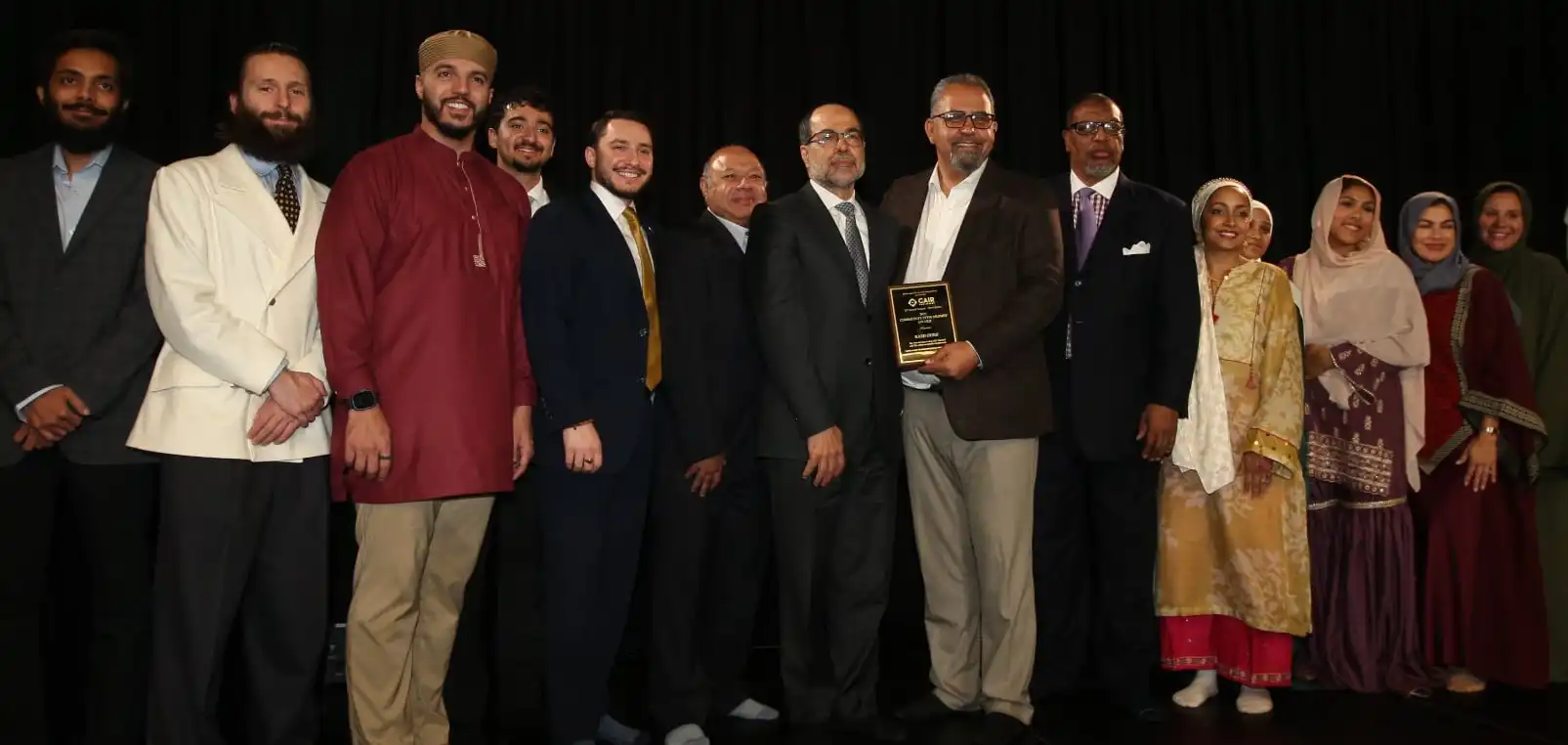 رائد عودة يحمل درع جائزة «رعاية المجتمع» على المسرح مع قيادات CAIR-NJ وأفراد من الجالية خلال الحفل السنوي العشرين في باترسون.